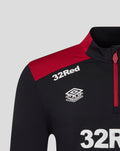 Close up of chest area on black training top showing 32Red sponsor and Umbro badge with red shoulder detail.