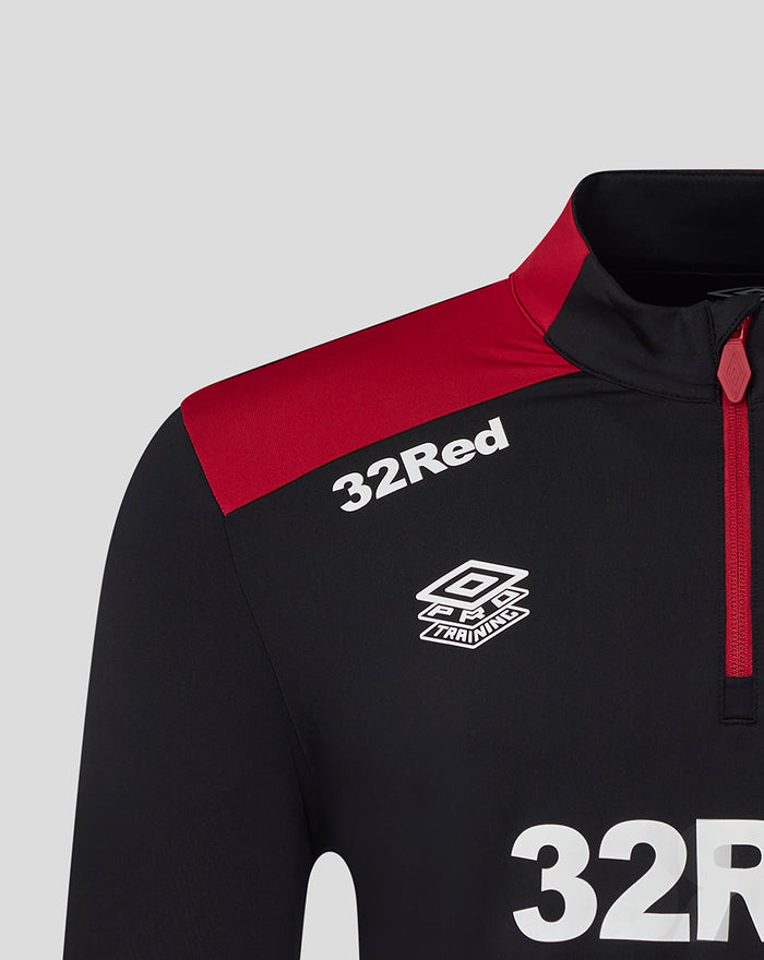 Close up of chest area on black training top showing 32Red sponsor and Umbro badge with red shoulder detail.