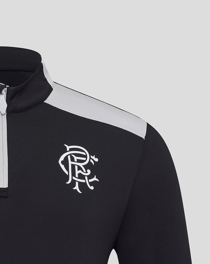 Close up of a black training quarter zip with a white club crest on the left chest