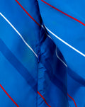 Close up of blue packable shower jacket fabric showing diagonal white and red stripes and zipper pull