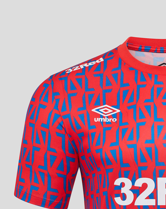 Front view of a unisex away matchday tee with red and blue geometric print, 32Red sponsor, Umbro logo and club crest.