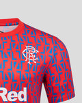 Close-up of red away shirt fabric with blue geometric print and white club crest on the chest.