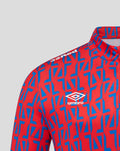 Close up of red away matchday quarter zip top with blue geometric pattern and Umbro logo on chest.