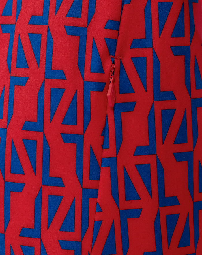 Close-up of red fabric with blue geometric print and a red zipper pull on the away jacket.