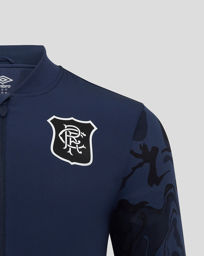 Close up of navy jacket chest displaying club crest and Umbro logo with camo sleeve panel