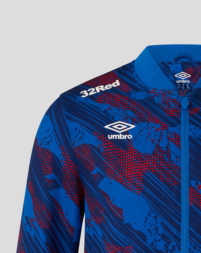 Shoulder and chest view showing 32Red and Umbro logos on the blue red print jacket with zip puller and collar