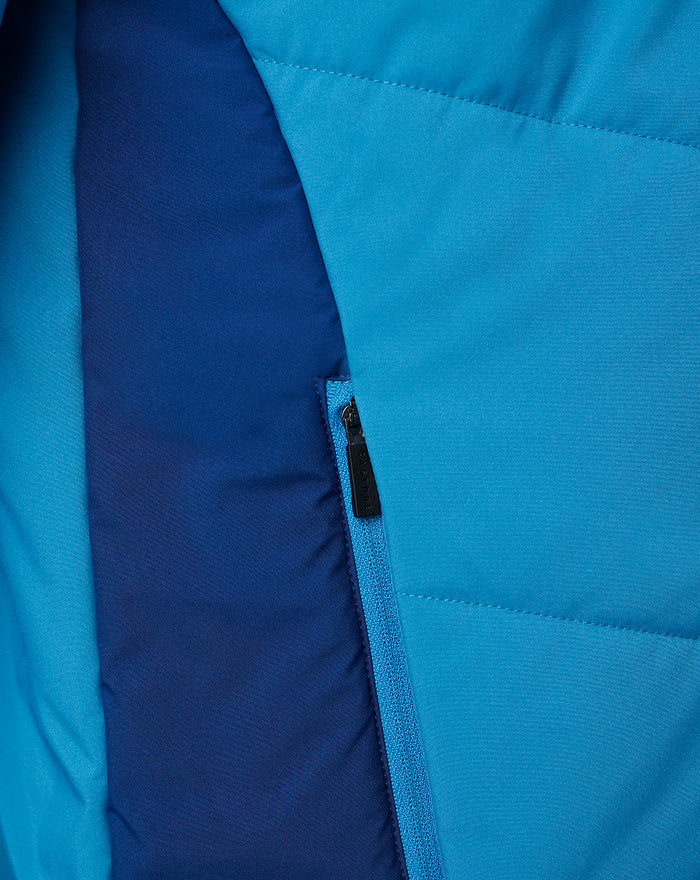 Close-up of blue training jacket pocket with vertical zipper and navy contrast panel.