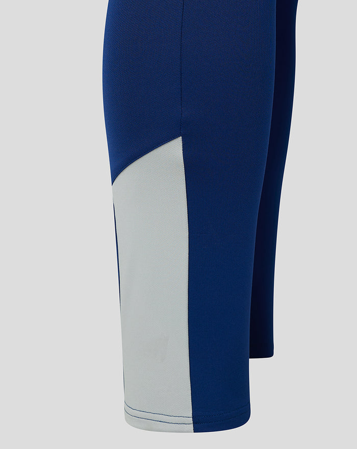 Close-up of blue training pant leg with a light grey panel and curved seam at the lower leg