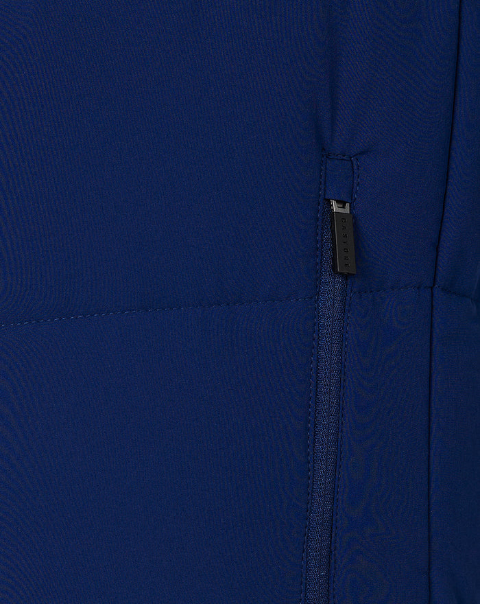 Close-up of deep blue City Print Hybrid Jacket fabric showing a vertical zip pocket and stitched seam.