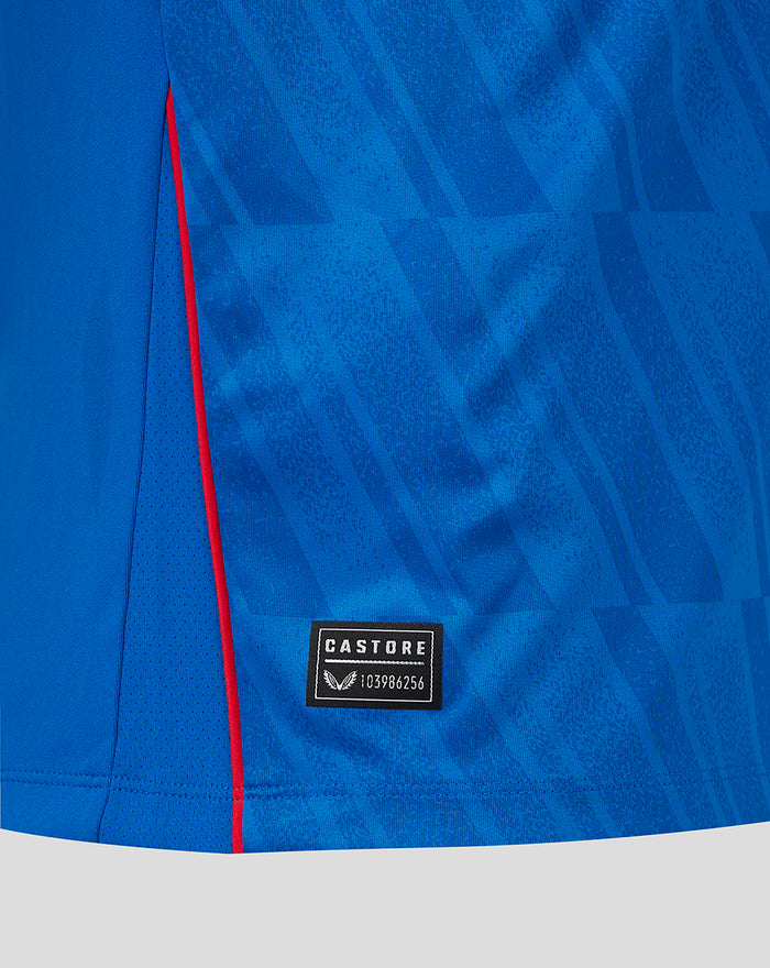 Side view of blue Rangers home shirt with red piping along the side seam and Castore patch near hem.