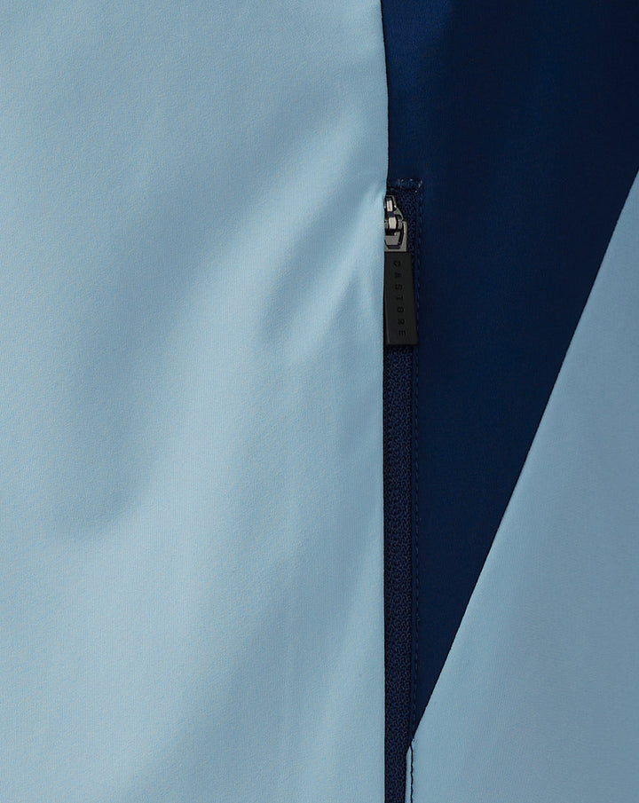 Close-up of light blue and navy rain jacket panels with a Castore branded zipper pull.