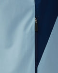 Close-up of light blue and navy rain jacket panels with a Castore branded zipper pull.