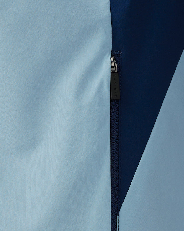 Close-up of light blue and navy rain jacket panels with a Castore branded zipper pull.