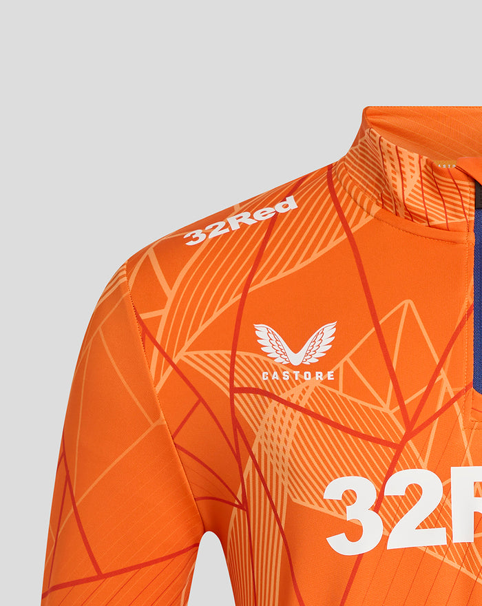 Shoulder close-up of the orange midlayer showing 32Red branding and the Castore winged logo with a blue zipper panel