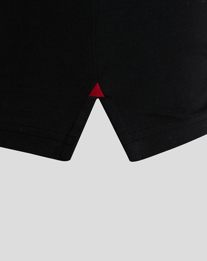 Lower front hem of black T shirt with a small red triangle stitch.