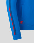 Close up of the blue hoodie sleeve with red and dark blue striped trim and a red lion emblem near the hem.