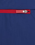 Close-up of blue nylon fabric with a red zipper pull on a men's anorak.