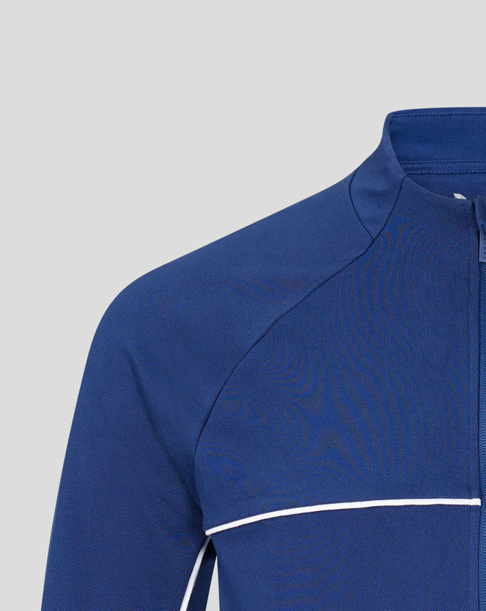 Blue track suit top close up showing white piping along the chest edge and fabric texture.