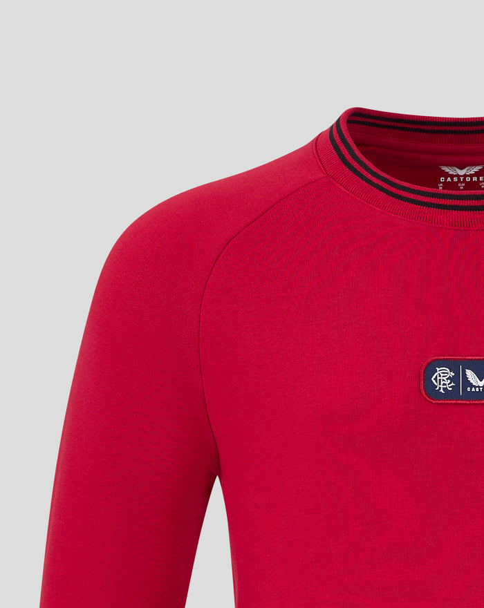 Close-up of red fleece crewneck highlighting striped collar and chest dual logo badge