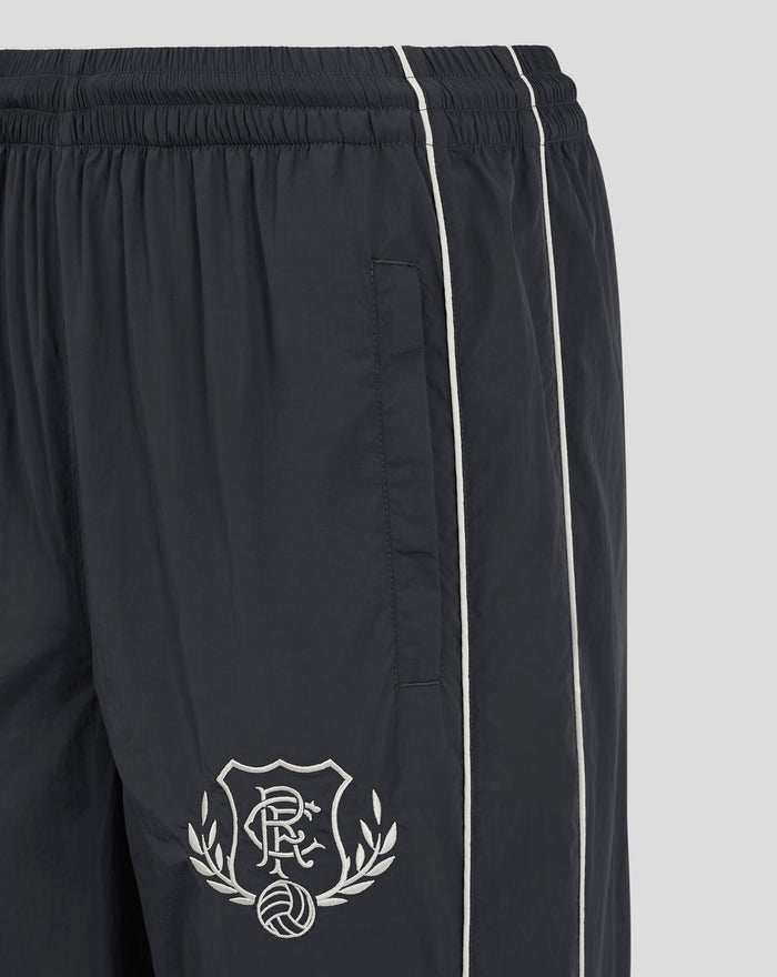 Close-up of dark Rangers FC tracksuit bottoms showing elastic waistband with knotted drawcords, white piping, and heritage crest on left thigh.