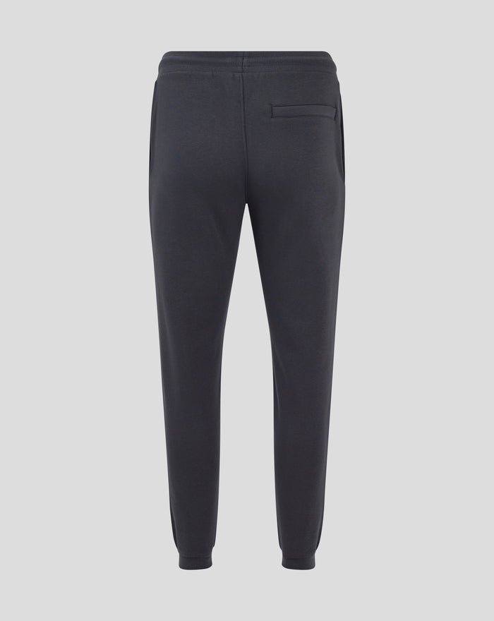 Rear view of dark brown joggers with ribbed cuffs and visible crest embroidery on the left thigh.