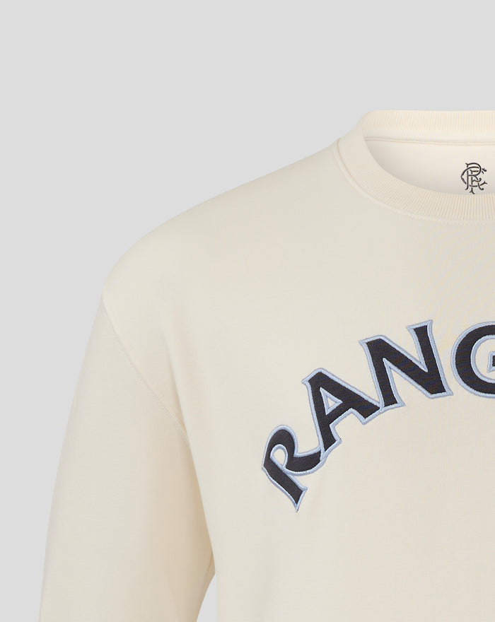 Shoulder and neck area of cream Rangers FC sweatshirt showing the small crest at the neckline and partial arched wordmark across the chest