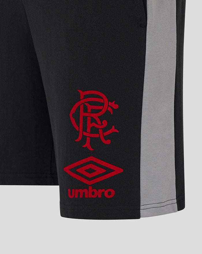 Close up of black shorts showing red crest and diamond Umbro logo at the hem with a grey side panel