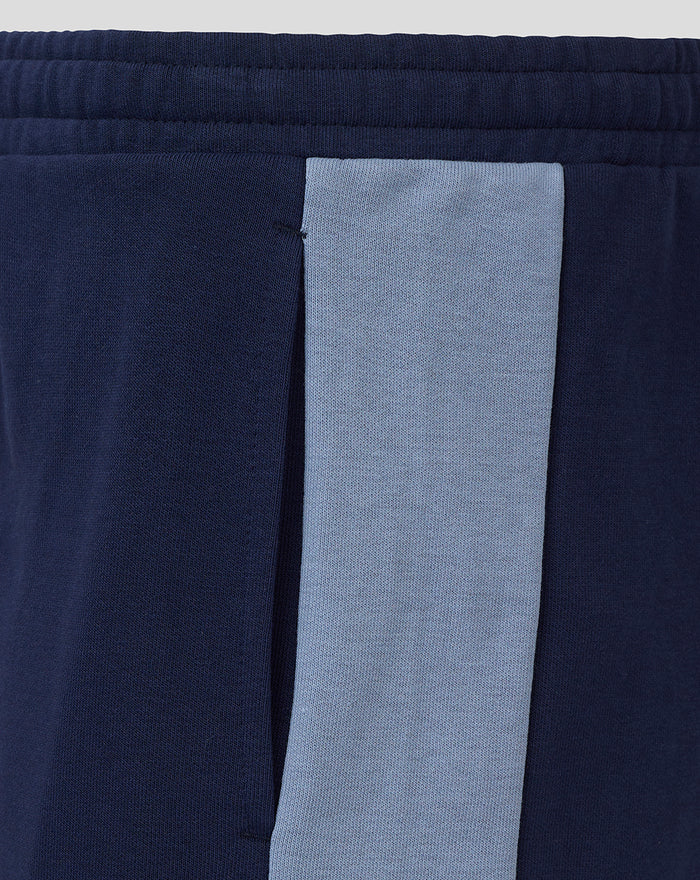 Close-up of navy shorts leg displaying blue club crest and Umbro diamond logo.
