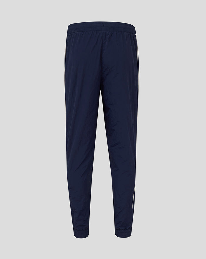 Back view of navy travel pant with white piping along legs and elastic waistband