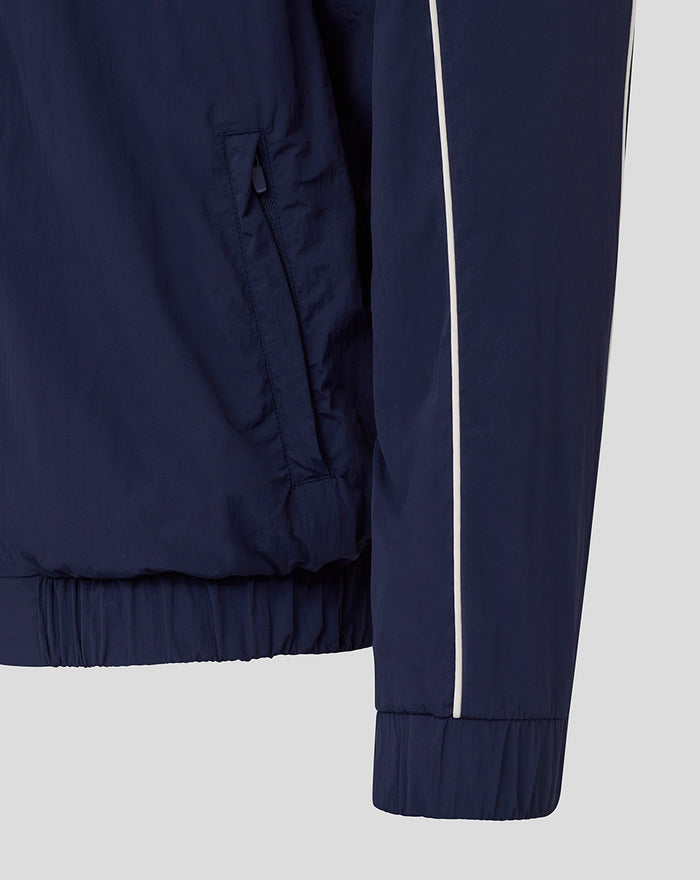 Close-up of navy travel track jacket showing zip pocket and zip detail at the hem