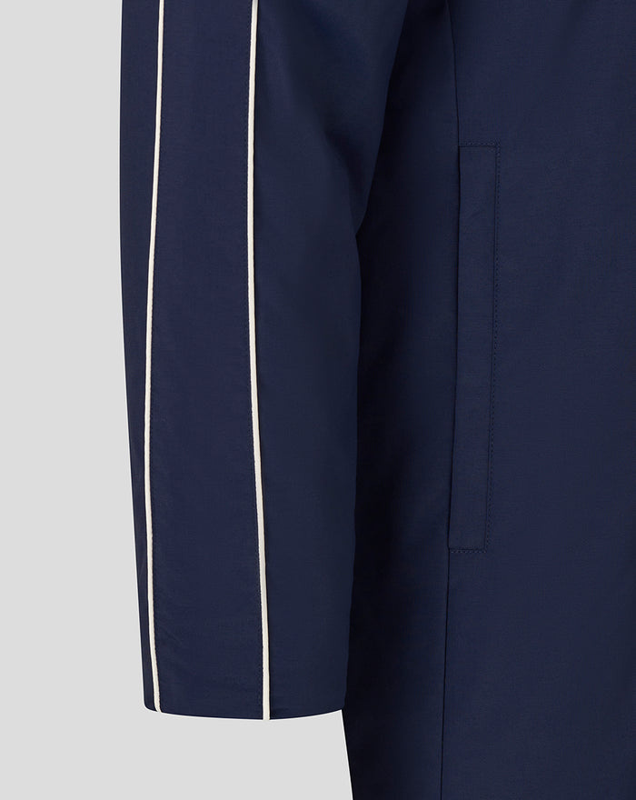Close up of a navy travel bench jacket sleeve with white piping along the seam