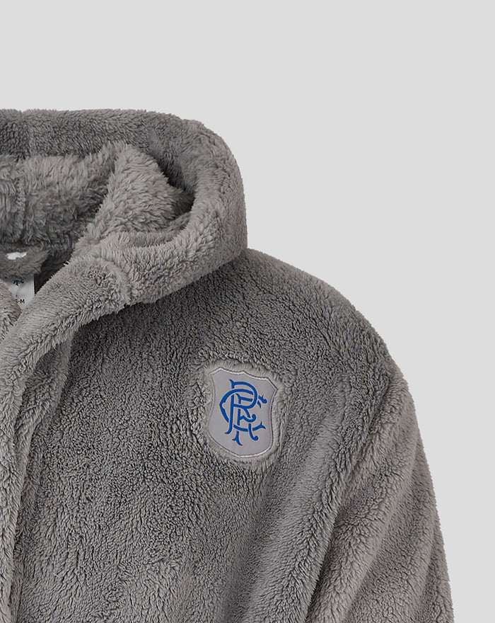 Close up of grey plush dressing gown showing soft fur texture and blue crest emblem on chest