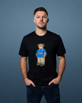 Model wearing black Rangers x Art of T-shirt with teddy bear graphic on the chest.