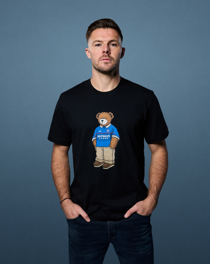 Model wearing black Rangers x Art of T-shirt with teddy bear graphic on the chest.