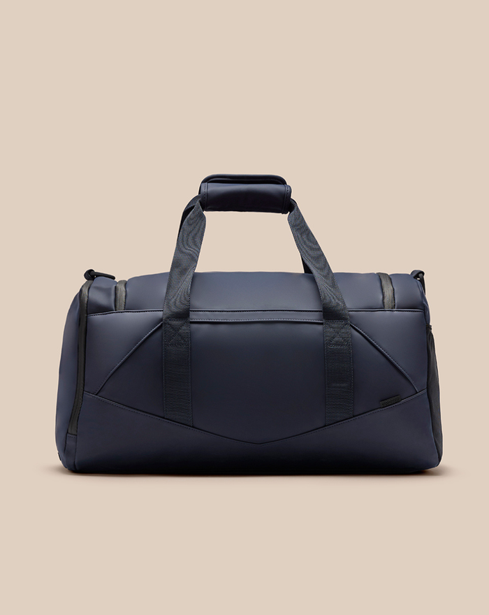 Navy CORE Holdall with dual top handles and a detachable shoulder strap against a beige background.