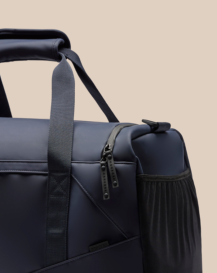 Close up of navy CORE Holdall showing zipper pull and side mesh pocket.