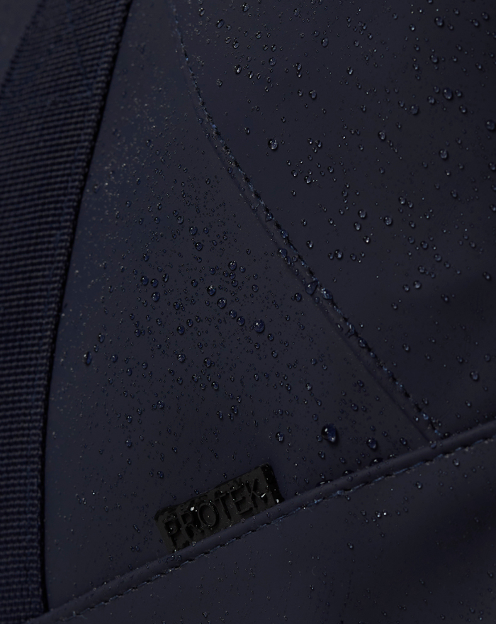 Close-up of navy CORE HOLDALL exterior with water droplets on rainproof fabric