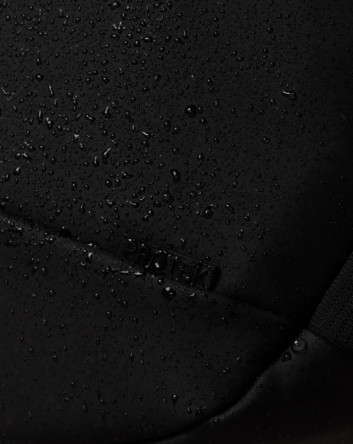 Close up of black water resistant fabric with droplets beading on the surface and PROTEK label