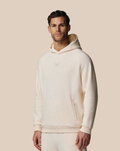 Beige cotton fleece hoodie worn by a male model against a soft tan background with a small chest logo