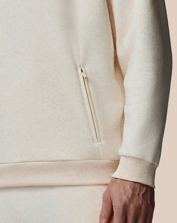 Beige cotton fleece hoodie with a zippered side pocket and ribbed hem.