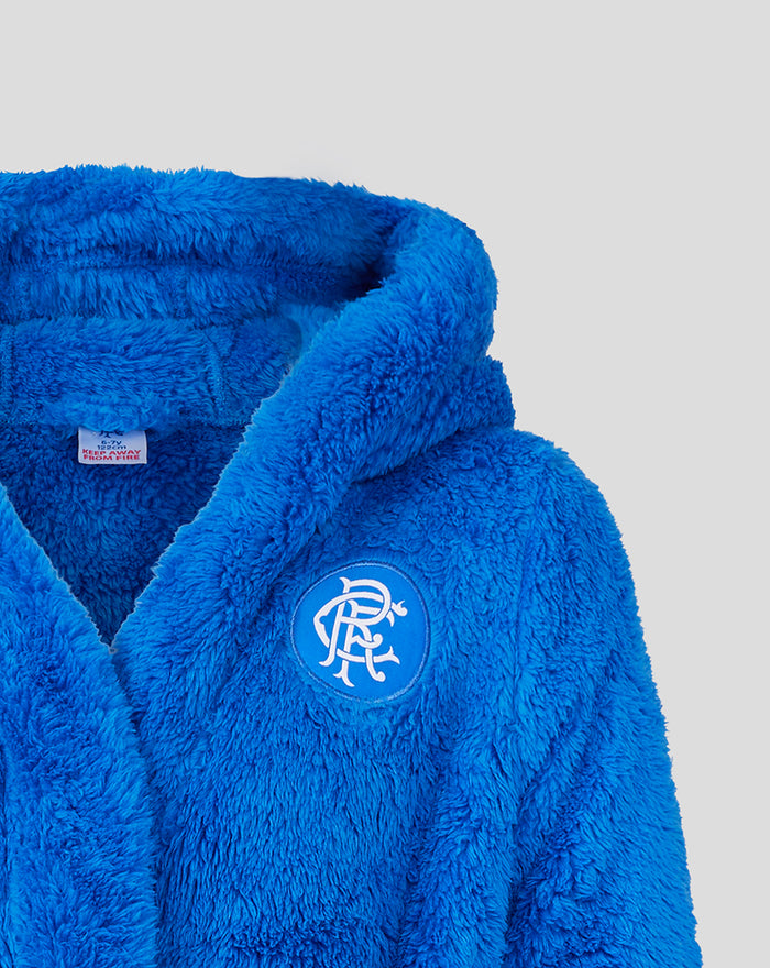 Close-up of the robe showing a round blue patch with white intertwined letters on the chest.
