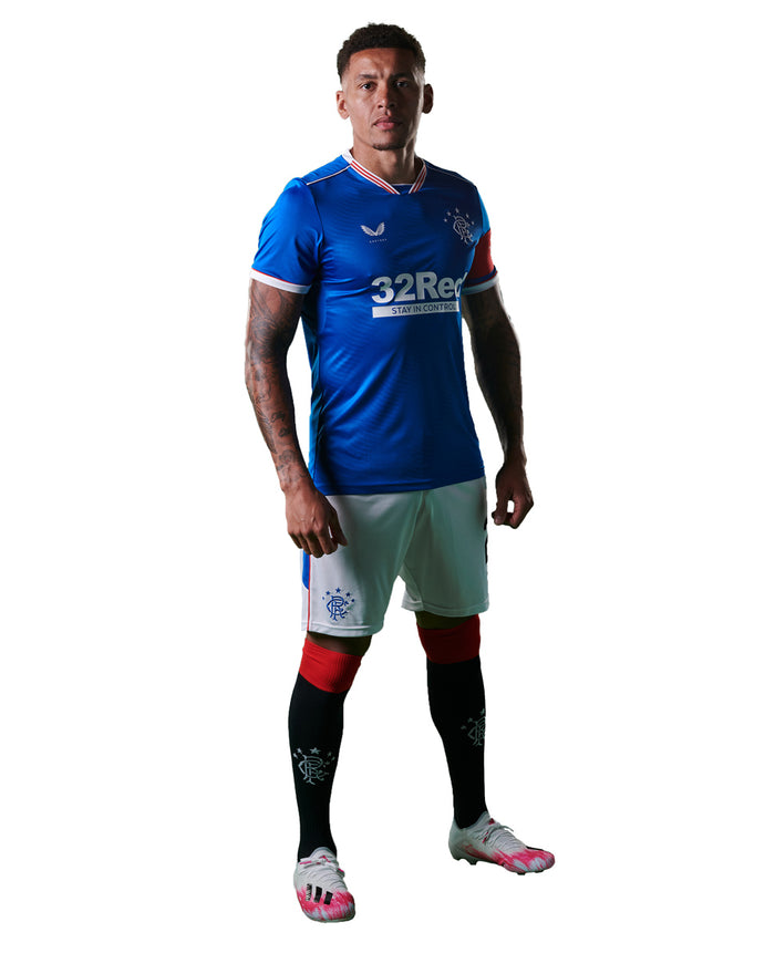 Model wearing blue Rangers junior home shirt with crest and sponsor, paired with white shorts and striped socks